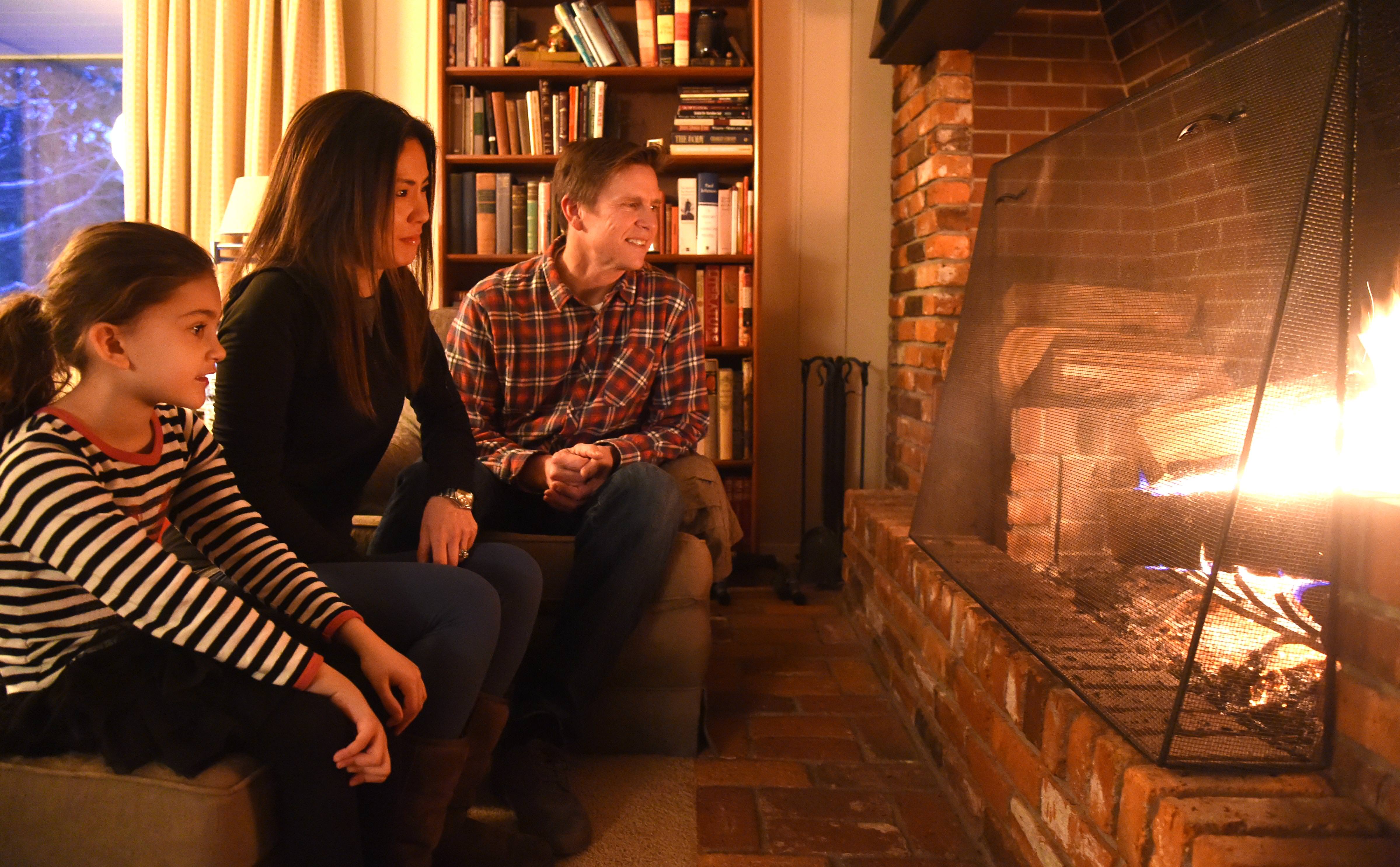 Patrick and Ting Vollmer with daughter Zoe, 6, sit in front of their fire place Friday, Nov. 27, 2015, after being one of the last customers to get power restored by the utility company. They stayed with family, eventually found a generator and survived the last few days. JESSE TINSLEY jesset@spokesman.com