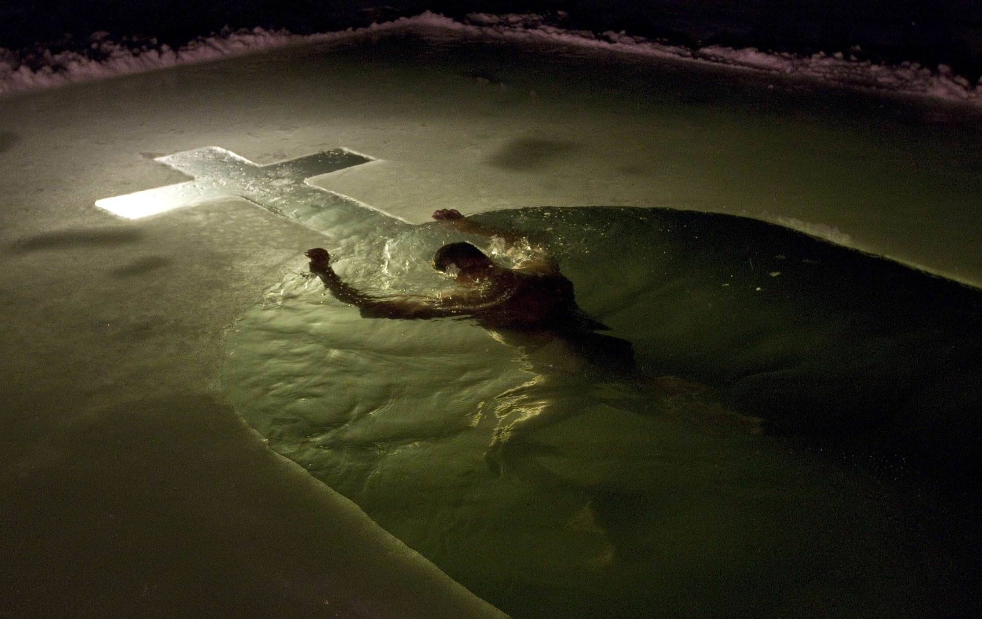 A man swims in a lake in Minsk, January 18, 2014. Orthodox believers mark Epiphany, which falls on January 19, by immersing themselves in icy waters regardless of the weather. REUTERS/Vasily Fedosenko (BELARUS - Tags: ENVIRONMENT SOCIETY RELIGION)