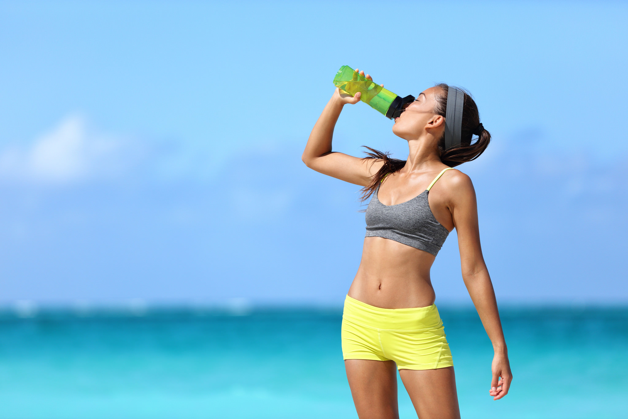 Fitness runner woman drinking water or energy drink of a sport b