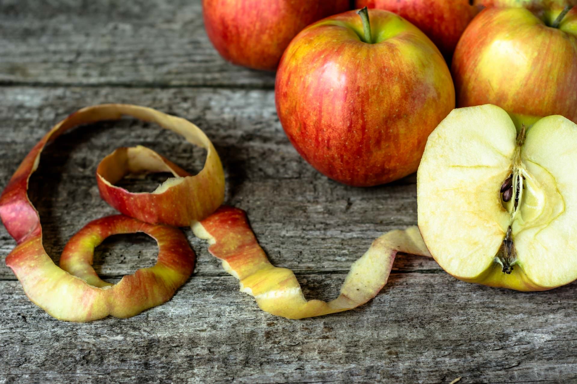 Whole apples and cut in half apple on wooden background