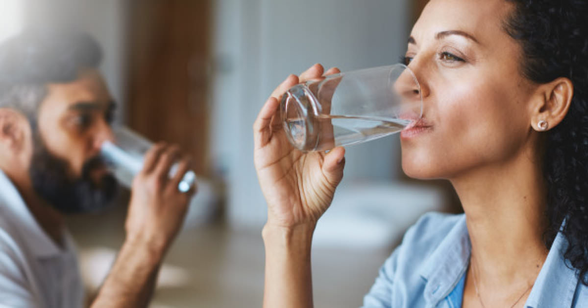 Shot of a couple drinking glasses of water together at home