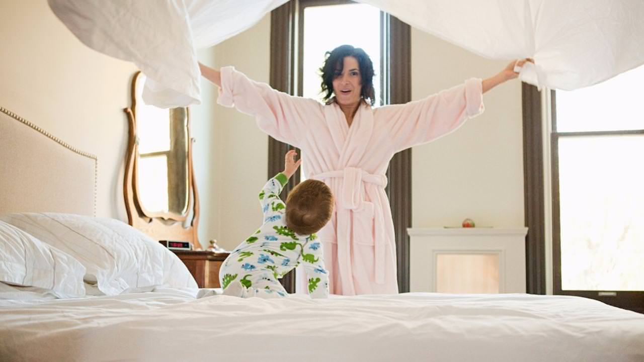 Mother and baby son making bed