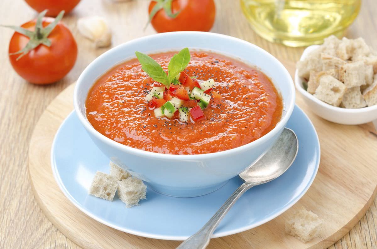 Bowl of cold tomato gazpacho soup with basil and croutons