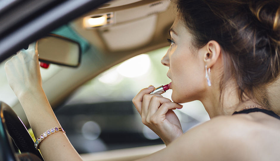 Beautiful woman paints her lips in the car