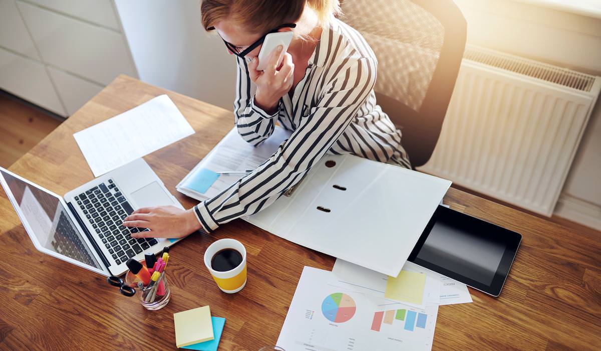 Successful businesswoman with an e-business working from an office at home telemarketing and taking orders over the phone or consulting with clients high angle view