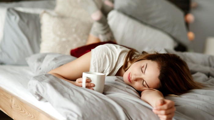 Woman with coffee reclining in bed