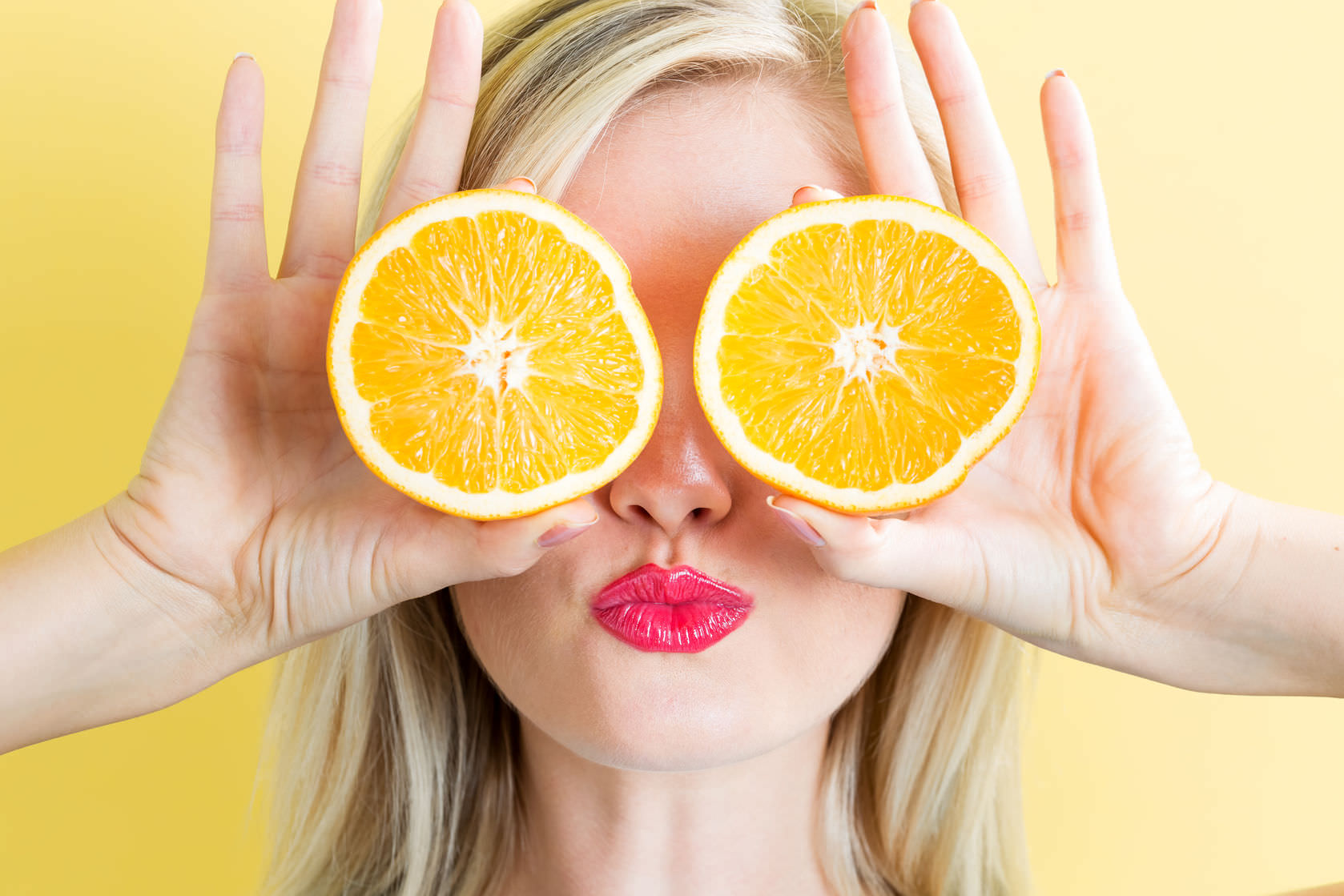 63993742 - happy young woman holding oranges on a yellow background