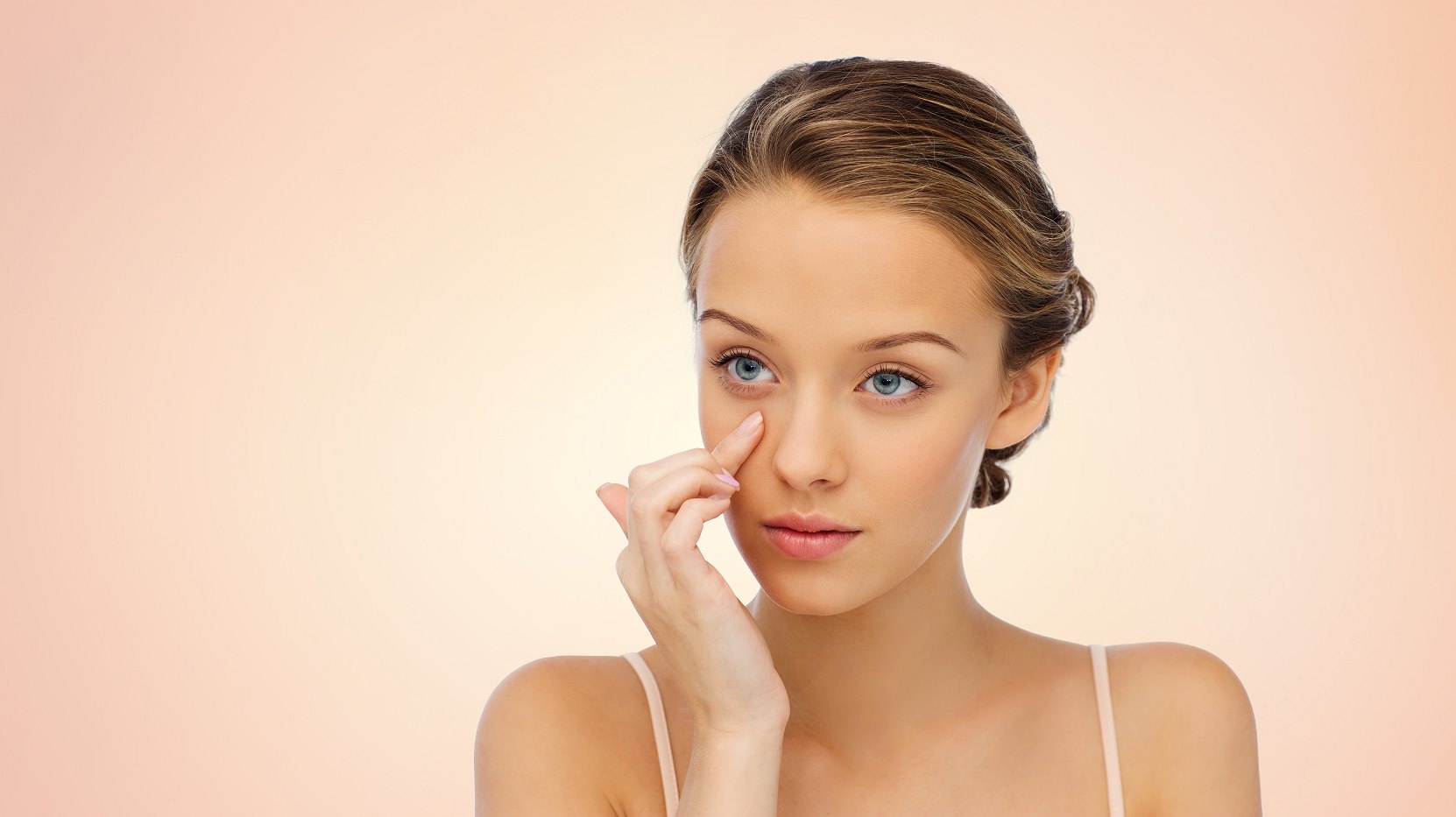 young woman applying cream to her face